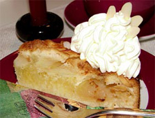 Ein Stck Apfelkuchen mit Sahnehaube und Mandelblttchen.