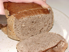 Ein Buchweizenbrot wird mit der Hand in Scheiben geschnitten!